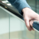 Side view of a person's hand holding shiny chrome handrail